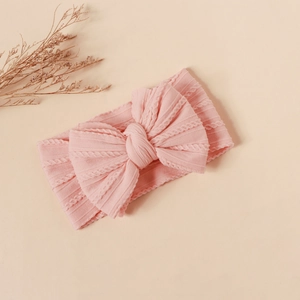 Close-up of pink cable knit nylon headband with a large bow detail for infants
