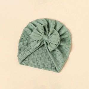 Detailed texture of bean green baby turban hat with a large decorative bow