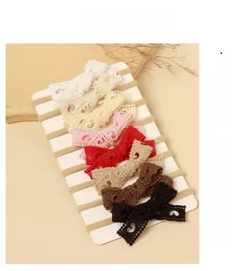Detailed set of seven colorful lace bow headbands for infants displayed on white card