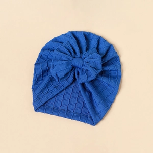 Detailed close-up of blue baby turban hat featuring a textured knit bow and ribbed fabric