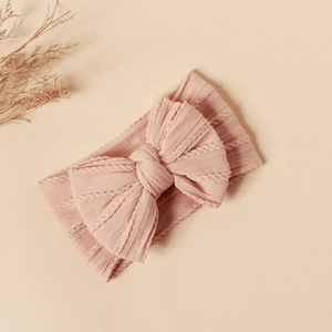 Detailed view of pink knitted baby headband featuring a large jacquard double bow decoration
