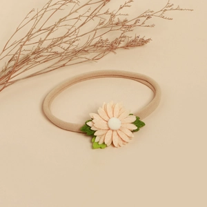 Détail d'un bandeau pour bébé en nylon rose avec fleur de marguerite en feutre faite main