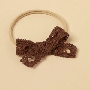 Close-up of dark brown lace bow hairband with hollow heart detail on soft nylon band