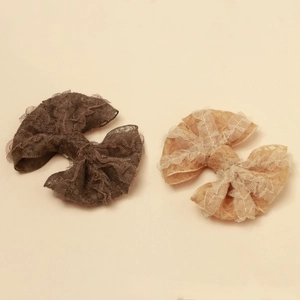 Détail de la texture dentelle superposée des barrettes nœuds marron foncé et beige