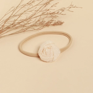 Détail d'une fleur blanche faite main sur un bandeau élastique doux pour bébé