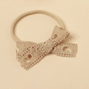 Close-up of baby lace bow headband featuring vintage beige crochet nylon texture