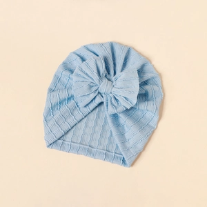 Macro detail of baby turban featuring light blue textured knit fabric and big bow