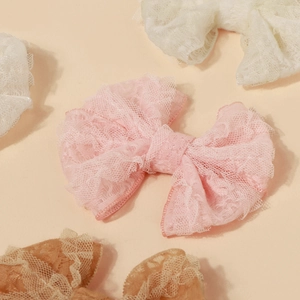 Détail de pinces à cheveux en dentelle rose et crème avec nœuds multicouches