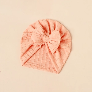 Soft pink infant turban hat with large bow detail and textured stretchy fabric