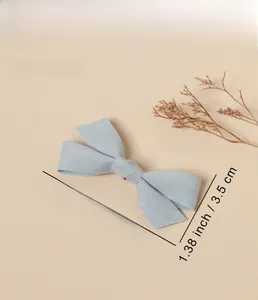 Detail of light blue bow hair clip with textured fabric and specific size measurements
