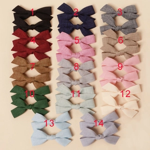 Flat lay display of fourteen pairs of handmade fabric bow hair clips in multiple colors