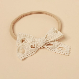 Close-up of baby lace headband featuring an intricate hollow heart pattern and soft nylon band