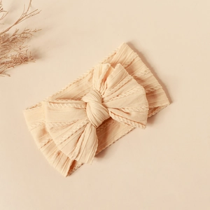 Close-up of cream double-layer knit bow nylon headband for babies with texture detail