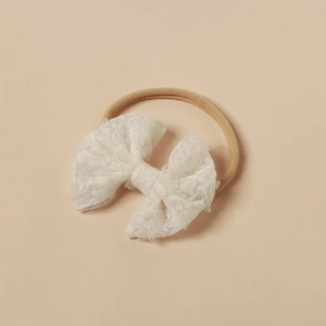 Detailansicht der weißen Spitzen-Schleife mit elastischem Nylon-Stirnband für Babys