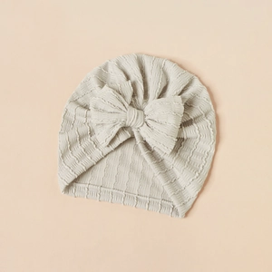 Detailed view of grey baby turban hat with popcorn fabric texture and large bow