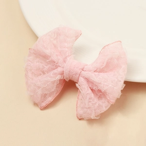 Détail de la pince à cheveux noeud en dentelle rose avec texture de maille et volants