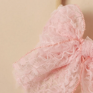 Close-up of pink lace bow featuring delicate mesh texture and scalloped edges for hairbands