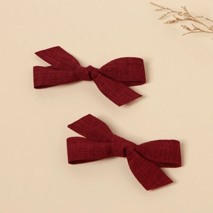 Close-up of wine red handmade fabric bow hair clips with textured fabric grain