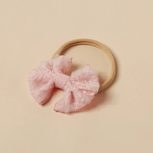 Detailaufnahme der rosa Spitzenschleife und des hochelastischen Nylon-Haarbandes für Babys