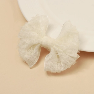 Détail de pince à cheveux avec nœud en dentelle blanche montrant la texture délicate