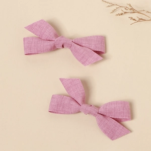 Detailed macro view of pink fabric bow hair clips showing linen texture and handmade quality