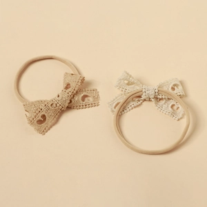 Detailed view of handmade lace bow baby headbands in beige and soft yellow colors