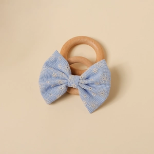 Détail de la barrette bébé avec nœud brodé bleu sur des anneaux en bois naturel