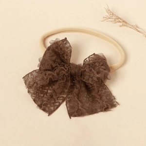 Detailed close-up of a large vintage dark brown lace mesh bow on a cream nylon baby headband