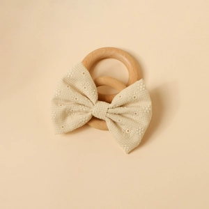 Détail de la broderie florale sur un nœud en coton beige avec anneaux en bois