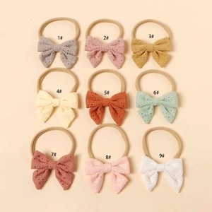 Detail view of 9pcs baby nylon headbands with delicate hollow embroidered bows in soft colors
