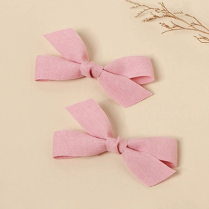 Close-up of pink fabric bow hair clips with textured linen material and handmade knots