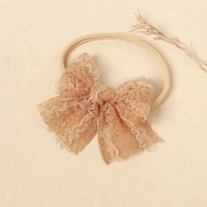 Detail of warm beige lace bow baby headband with soft high elastic nylon band