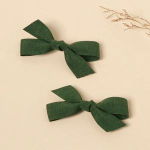 Close-up of handmade dark green fabric bow hair clips with natural linen texture