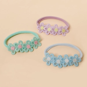 Detailed view of three soft nylon baby headbands with delicate embroidered floral patterns