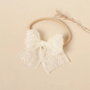 Close-up of baby lace bow headband featuring detailed textures and soft elastic nylon band
