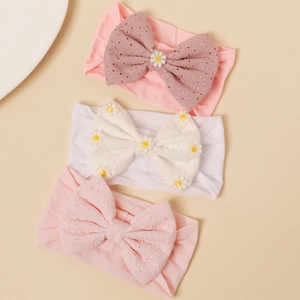 Detailed close-up of three baby nylon headbands with floral embroidery and bow design