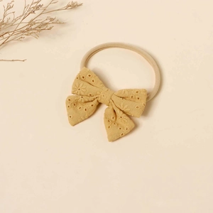 Detail of yellow cotton bow headband with embroidered floral pattern and nylon band