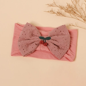 Close-up of pink baby headband with lace bow and cute cherry decorative element