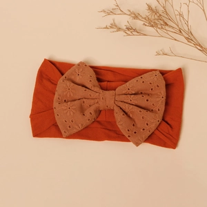 Detailed view of rust red baby headband with beige eyelet embroidery bow knot
