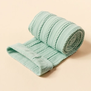 Soft light green knitted nylon baby headband with elegant vertical cable knit pattern