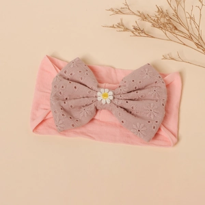 Detailed view of pink baby headband with embroidered bow and 3D daisy decoration