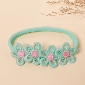 Detailed macro view of mint green nylon baby headband with delicate floral lace embroidery