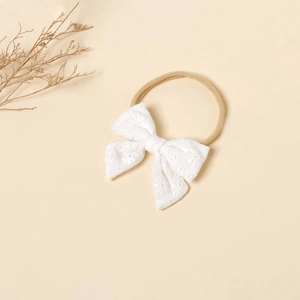 Close-up of baby lace bow headband with delicate floral embroidery on nylon band