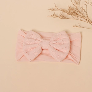 Detail of baby pink nylon headband with a large eyelet embroidery hollow bow