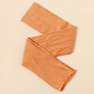 Detail of ginger yellow knitted nylon headband featuring cable knit texture for babies