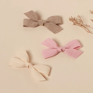 Detail shot of three linen bow hair clips in brown, pink, and cream with dry flowers