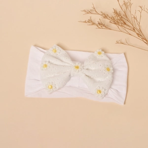 Detail of white nylon baby headband with large lace bow and yellow daisy embroidery