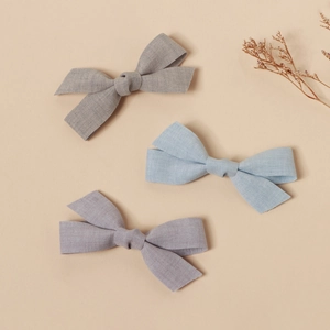 Close-up of handmade linen bow hair clips in grey, blue and lilac for children