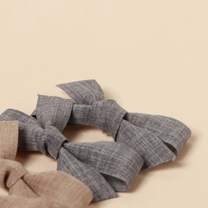 Close-up of grey and beige handmade fabric bow hair clips with textured linen weave