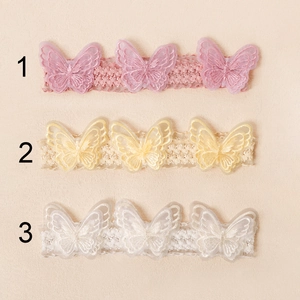 Detailansicht von drei Baby-Spitzenstirnbändern mit bestickten Schmetterlings-Patches in Pastell